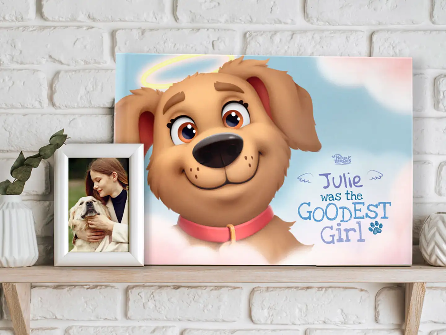 Personalized dog memorial canvas titled "Julie Was the Goodest Girl" by Hooray Heroes displayed on a shelf with a framed photo of the owner and pet.